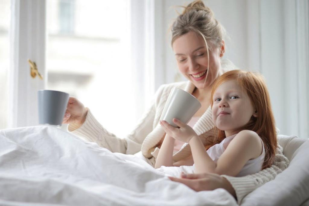 Mother and daughter holding mugs in a bed